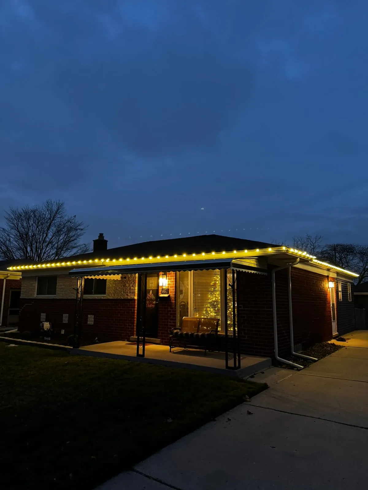 Warm white Christmas lights installed along the gutter line of a brick home